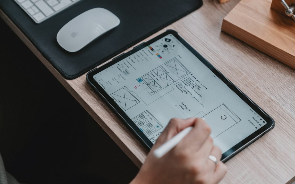 A designer sketching interface wireframes on a tablet